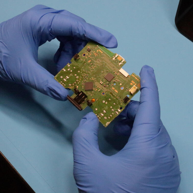 Controller circuit board being inspected by hand